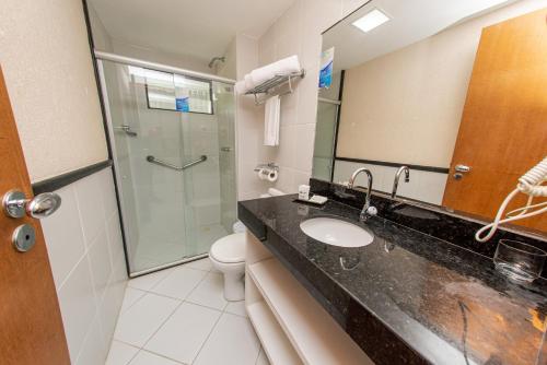 uma casa de banho com um lavatório e um chuveiro em Nobile Inn Cabo Branco em João Pessoa