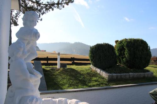 une statue d'un enfant dans une cour avec une clôture dans l'établissement Luxus-Landhaus im Schwarzwald/Baiersbronn mit Pool, à Baiersbronn