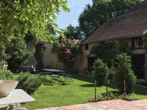 un jardin avec des tables et des chaises et un bâtiment dans l'établissement La maison Jeanne d'Arc, à Saint-Fargeau