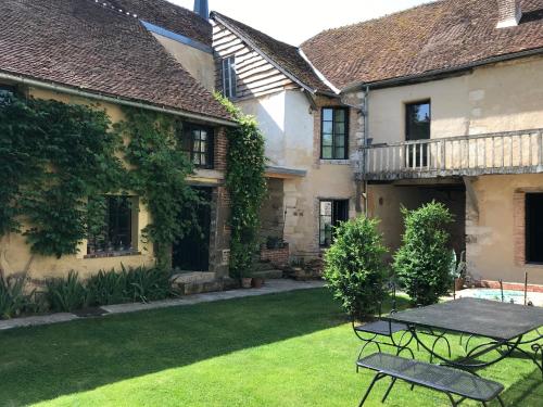 a patio with a table in the yard of a house at La maison Jeanne d'Arc in Saint-Fargeau