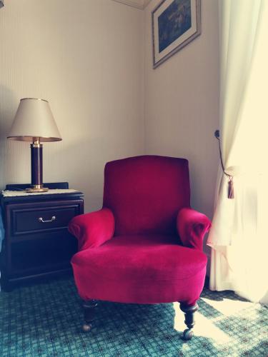 a red chair in a room with a lamp at Victoria Hotel in Blairgowrie