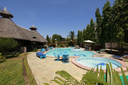 a large swimming pool with blue chairs and umbrellas at Jacyjoka Apartments Nyali in Mombasa