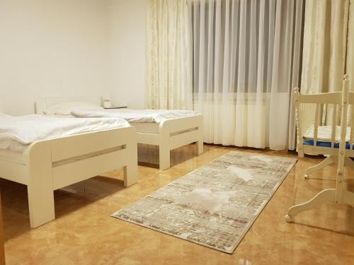 a bedroom with two beds and a crib and a rug at Apartment Paradise Enver in Dubrave Gornje