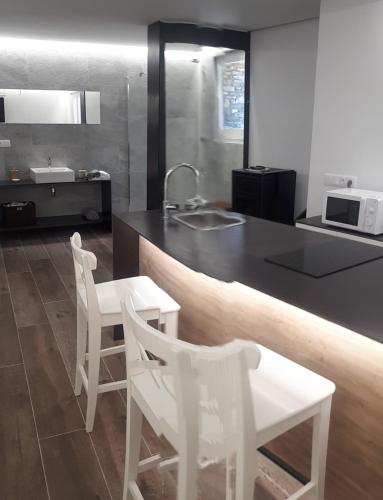 uma cozinha com um balcão, 2 cadeiras brancas e um lavatório em cal dalmau apartaments loft em Pardines