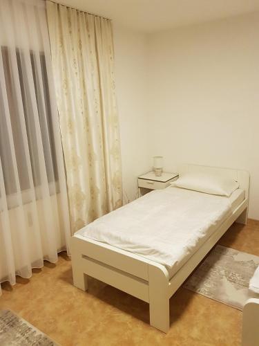 a white bedroom with a bed and a window at Apartment Paradise Enver in Dubrave Gornje