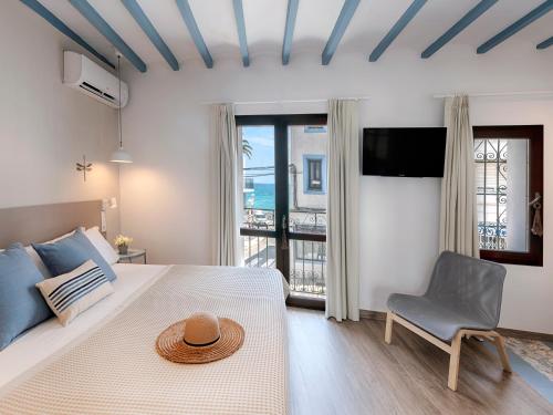 een slaapkamer met een bed, een stoel en een televisie bij Hostal Altea House in Altea