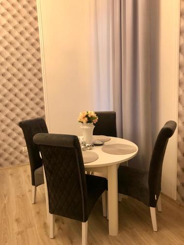 a table with chairs and a vase of flowers on it at Apartament Mickiewicza - PKP Station in Przemyśl