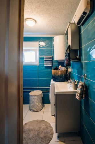 a blue tiled kitchen with a sink and a counter at The Meadow cabin in Žabljak