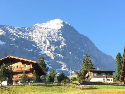 a snow covered mountain in front of a house at Mönch Amazing Apartment Grindelwald in Grindelwald