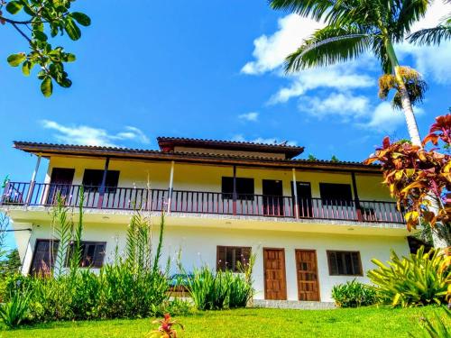 uma casa antiga com varanda e palmeiras em Flats vista bela com vista da montanha em Paraty