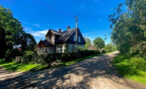 una casa al lado de un camino de tierra en Bright and cosy place at rustic house, en Vecumnieki
