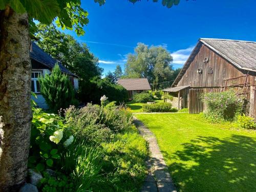 a garden with an old barn and a grass yard at Bright and cosy place at rustic house in Vecumnieki