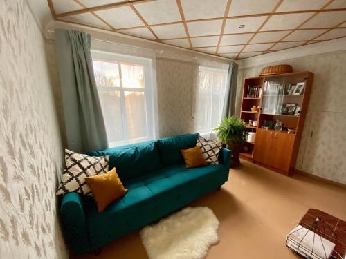 uma sala de estar com um sofá verde e uma janela em Bright and cosy place at rustic house em Vecumnieki