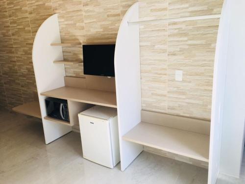 a room with a tv and a white cabinet at Hotel das Palmas in Florianópolis