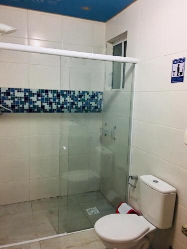 a bathroom with a toilet and a glass shower at Hotel das Palmas in Florianópolis