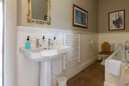 a bathroom with a sink and a toilet and a tub at Plas Maenan in Conwy