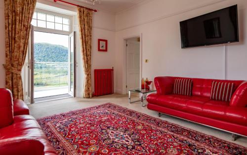 a red couch in a living room with a window at Plas Maenan in Conwy