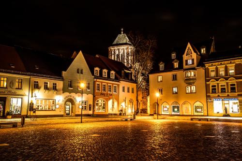 een stad 's nachts met een klokkentoren op de achtergrond bij Markt 15 Gästehaus in Senftenberg