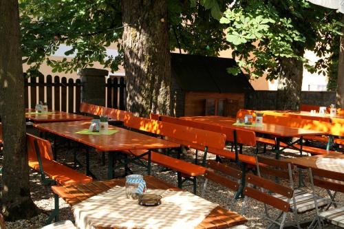 Landgasthof Fischer Veri في Mitterfels: مجموعة طاولات وكراسي خشبية تحت شجرة
