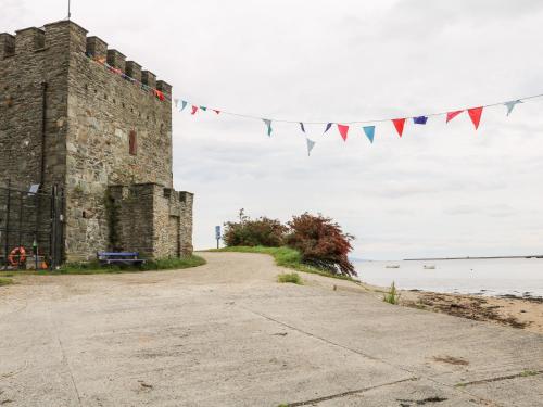 a castle with flags hanging from it next to the water at Culmore Point in Culmore
