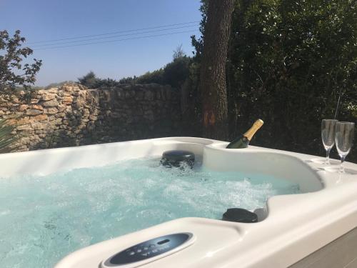 a hot tub with a bottle and two wine glasses in it at Les Mazets et Spa D'Uzes in Arpaillargues-et-Aureillac