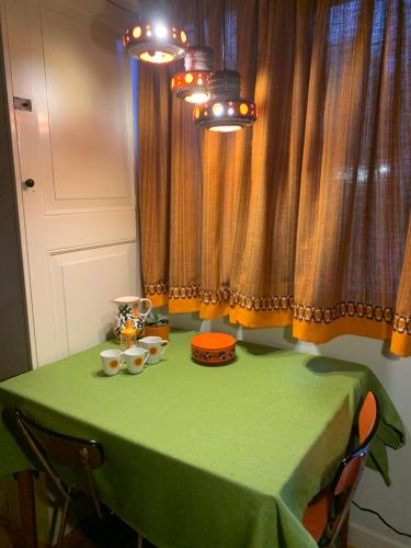 a table with a green table cloth and cups on it at Retro-huisje GoedFout in Olst
