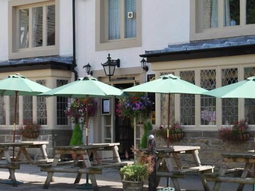 a group of picnic tables with umbrellas in front of a building at The Miners Arms in Eyam