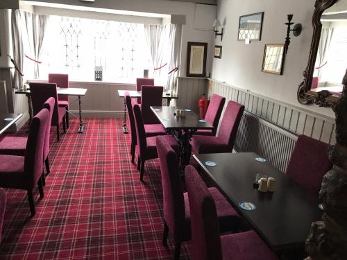 a dining room with red chairs and tables in a restaurant at The Miners Arms in Eyam