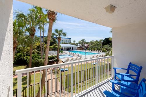 a balcony with blue chairs and a swimming pool at The Island Resort at Fort Walton Beach in Fort Walton Beach