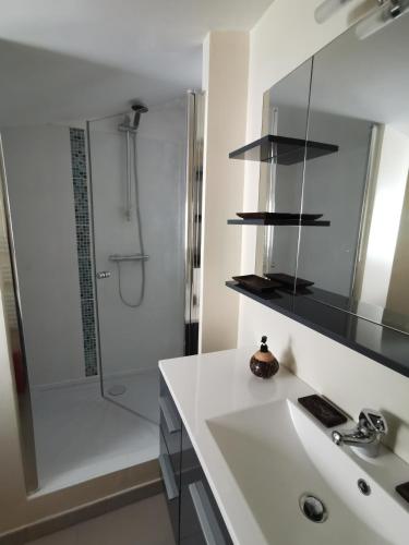 une salle de bain blanche avec un lavabo et une douche dans l'établissement Parfum d'Angkor, à Colleville-Montgomery