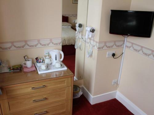 een kleine kamer met een koelkast en een tv aan de muur bij Merton House in Worthing
