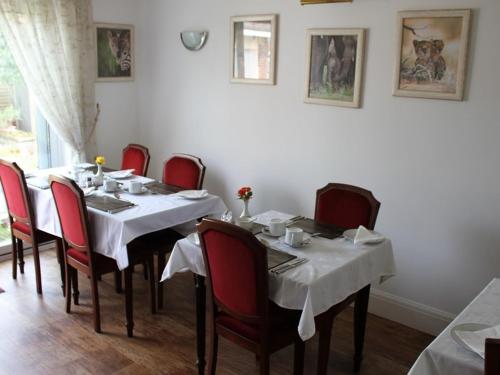 a dining room with a table and red chairs at Merton House in Worthing