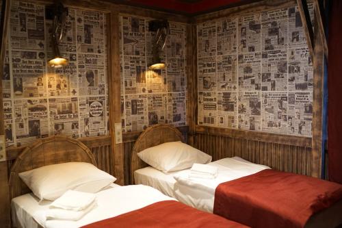 two beds in a room with newspapers on the wall at Aparthotel MyCologne in Cologne
