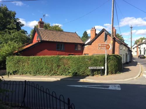 a red house on a street with a street sign at Myrtle cottage in Dickleburgh