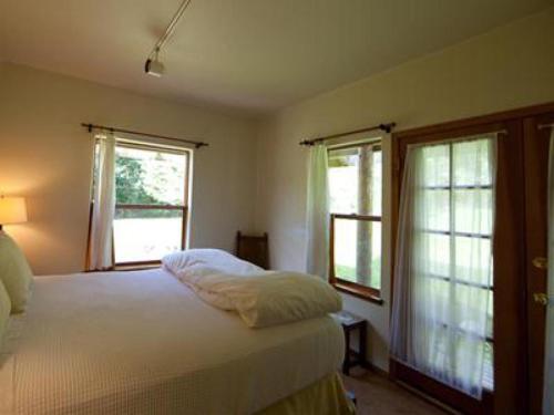 a bedroom with a white bed and two windows at Nettles Farm in Lummi Island