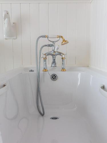 a white bath tub with a faucet in a bathroom at Plas Maenan in Conwy
