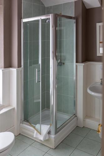 a shower with a glass door in a bathroom at Plas Maenan in Conwy