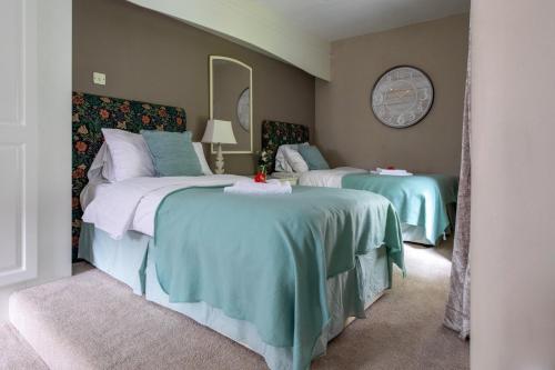 a bedroom with two beds and a mirror at Plas Maenan in Conwy