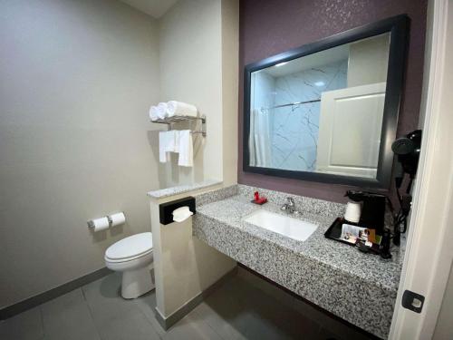 y baño con lavabo, aseo y espejo. en SureStay Plus Hotel by Best Western Ada, en Ada