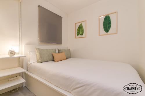 マドリードにあるCharming Santa Isabelの白いベッド1台、壁に2枚の写真が飾られたベッドルーム1室