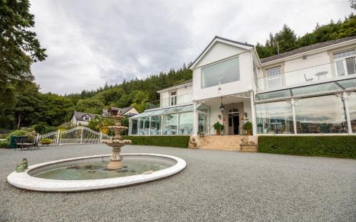 uma casa com uma fonte em frente a um edifício em Plas Maenan em Conwy