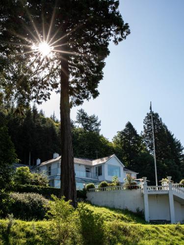 a house with a white fence and a tree at Plas Maenan in Conwy