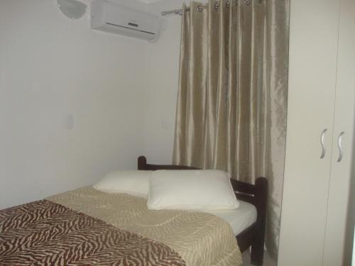 1 dormitorio con cama y ventana con cortina en Studio 80m da Praia, en Bombinhas