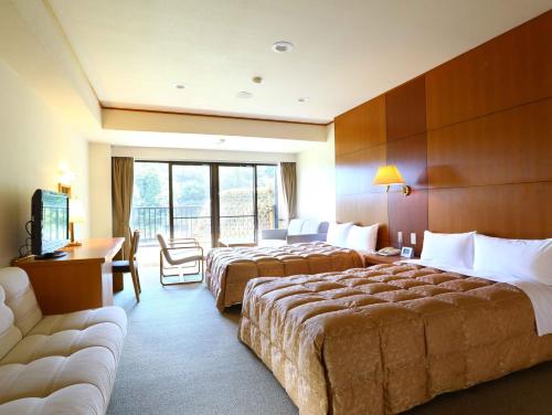 a hotel room with two beds and a couch at Yugawara Chiyodaso in Yugawara