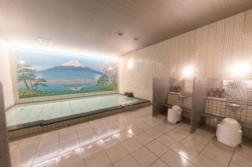 a bathroom with a bath tub with a painting of a mountain at Yugawara Chiyodaso in Yugawara