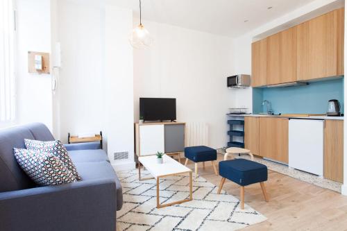 a living room with a blue couch and a kitchen at Luminous Appt And Design Close To The Sacred Heart in Paris