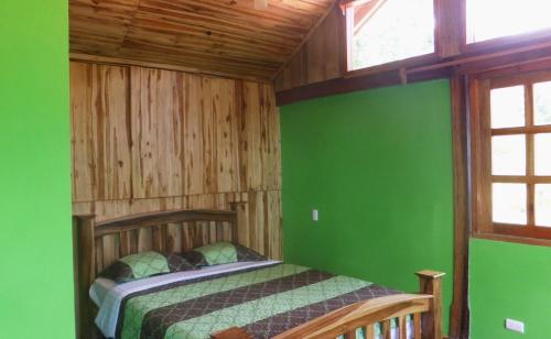 1 dormitorio con paredes verdes y cama de madera en Centro Ecoturístico Flor de Pochote en El Pochote
