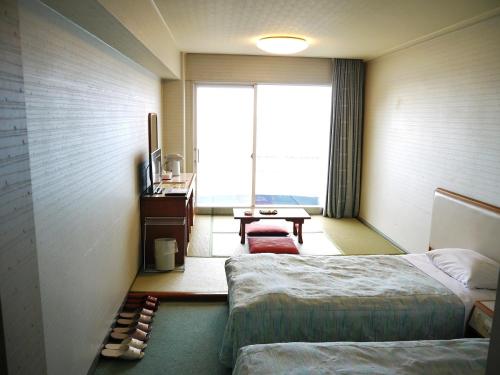 ein Hotelzimmer mit 2 Betten und einem Fenster in der Unterkunft Nishiizu Matsuzaki Itoen Hotel in Matsuzaki
