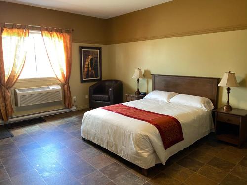 1 dormitorio con 1 cama, 1 silla y 1 ventana en Motel le Phare, en Plessisville