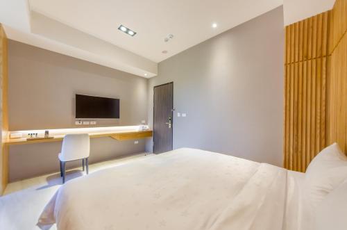 a bedroom with a bed and a desk and a tv at The Lin Inn in Kenting